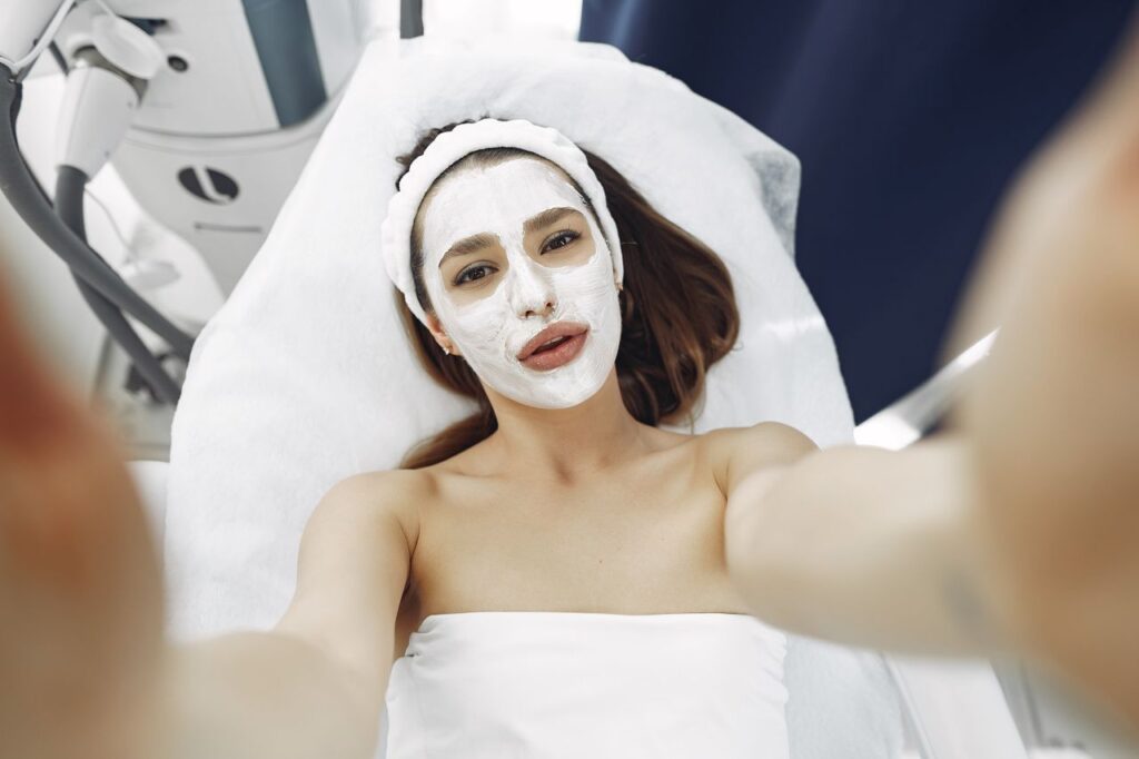 A woman enjoys a relaxing spa facial treatment with a moisturizing mask indoors. Perfect for wellness and skincare concepts.