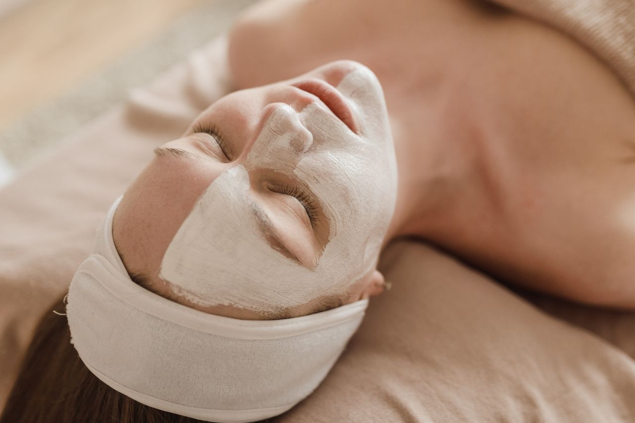 Services A serene woman enjoying a skincare treatment with a facial mask at a spa.